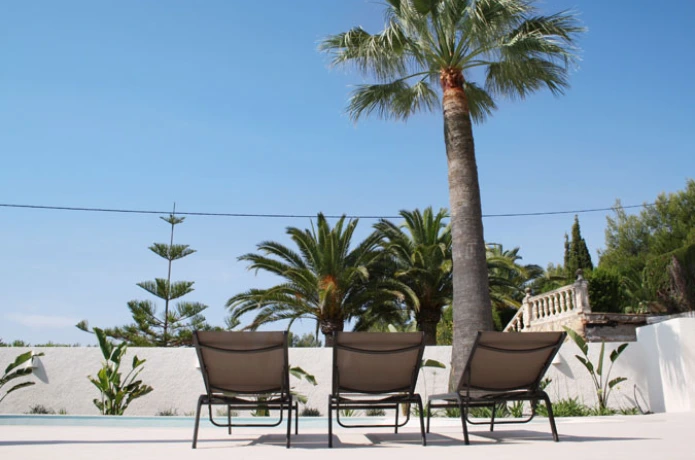 Zonneterras met palmen en ligbedden bij villa La CaSam